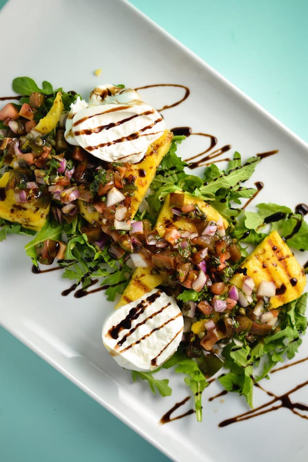 Grilled polenta slices add smokiness to arugula, creamy burrata and a tomato-caper salad. This flavorful side is sure to be a backyard classic.
