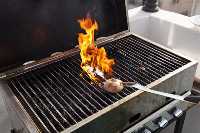 Getting the grill ready for some cooking - rubbing halved onion on the hot grate.