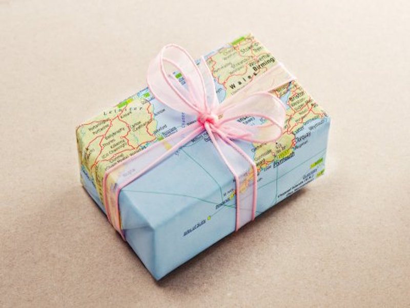 A bon voyage gift for travelers wrapped with map paper and pink bow. (Thinkstock photo)