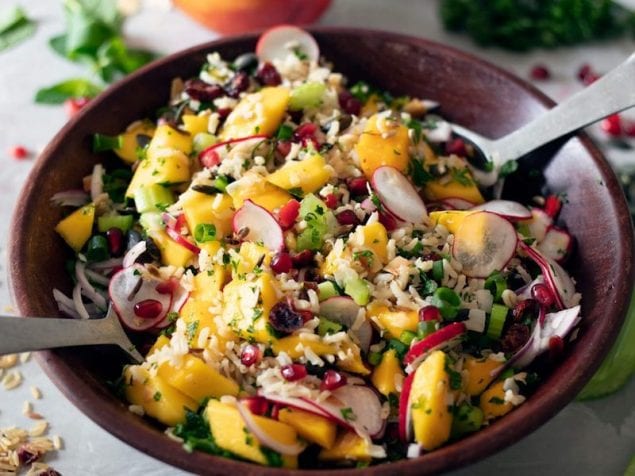 A super food, plant-based rice salad packed with fresh ingredients including mango, red onion, radish, celery, chili, herbs, pomegranates and cranberries.