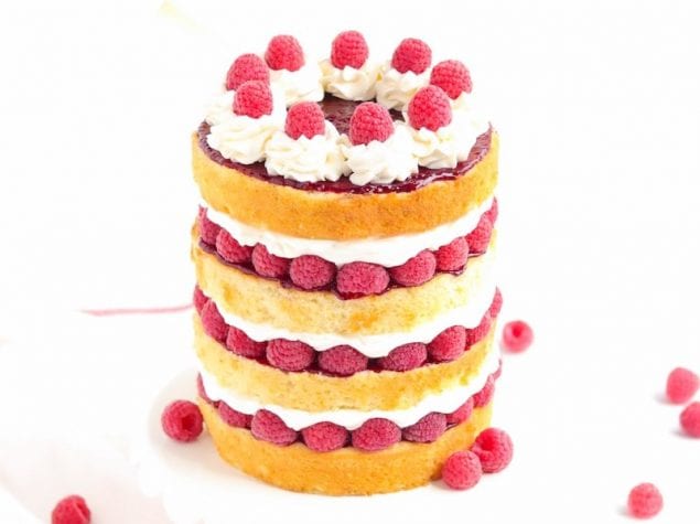 Golden layers of moist vanilla cake are layered between a fluffy cream filling with raspberry compote, and fresh raspberries in this Stacked Raspberries and Cream Cake.