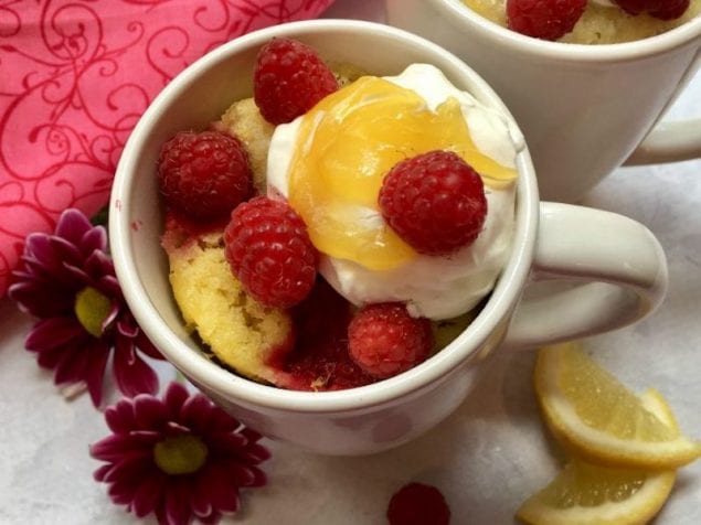 A Raspberry Lemon Mug Cake, hot out of the microwave and topped with whipped topping, lemon curd and fresh raspberries, a perfect, quick treat.